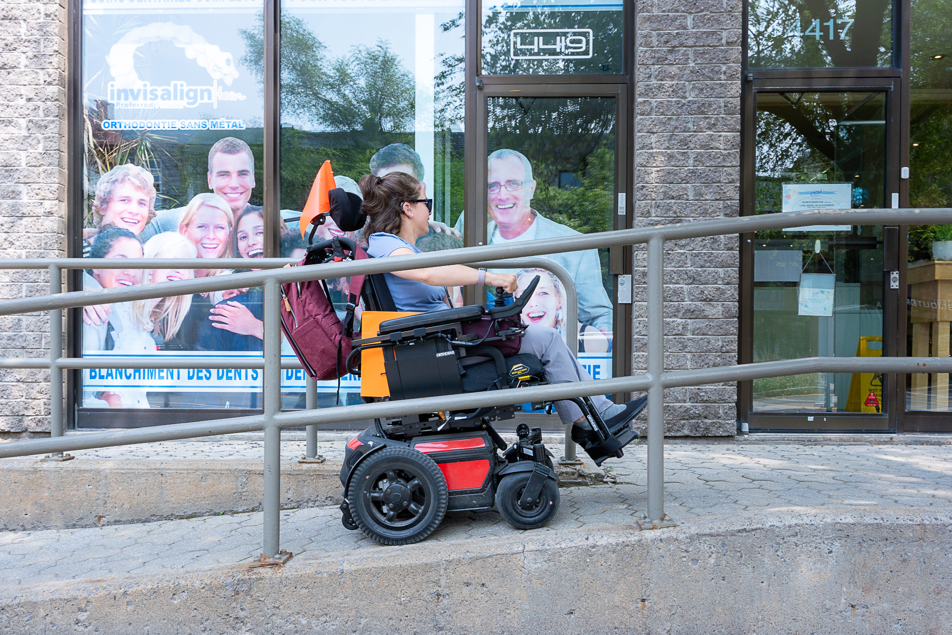 une femme en fauteuil roulant électrique monte une rampe en bêton