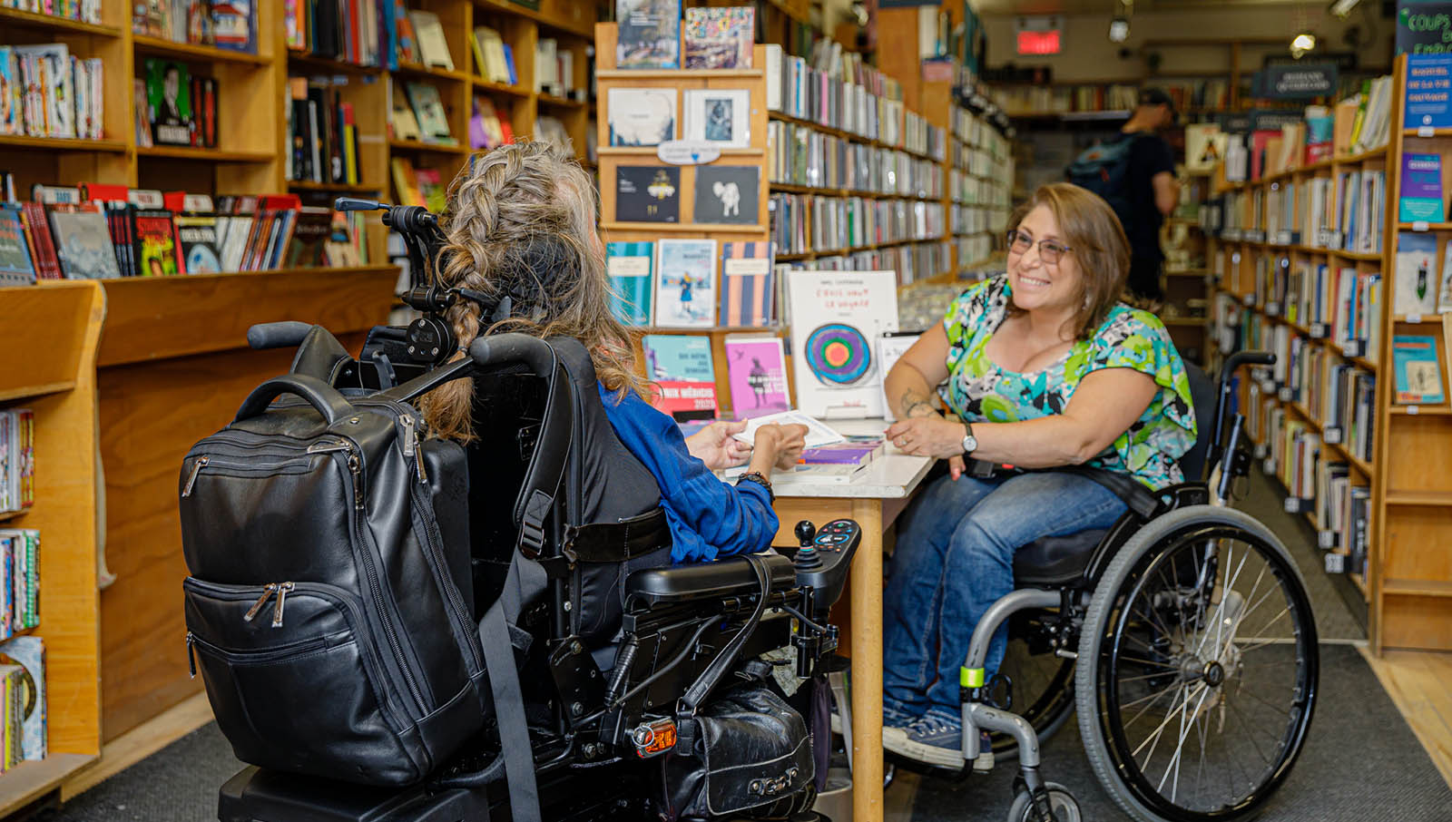 deux femme en fauteuil roulant discutent dans une librairie